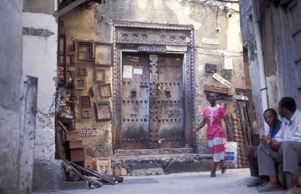 Tanzanya 'nın Zanzibar Adası' ndaki Taş Kasaba 'nın geleneksel ahşap kapısındaki yerli bir kadın. Tanzanya, Zanzibar, Taş Şehir, Ekim 2004