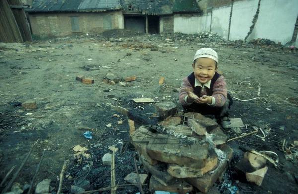 Çin 'in Shaanxi Provinz bölgesindeki eski Xian şehrindeki Müslüman Mahallesi' nin ara sokağında sıcak bir yangında bir çocuk. Çin, Xian, Ekim 1997