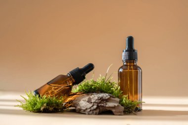Kozmetik yağlı cam damlatan şişeler, esaslı veya serumlu ve pastel bej arka planda izole edilmiş yeşil yosun. Doğal organik spa kozmetik konsepti. Bitkisel homeopatik ürünler. Damgalama modeli