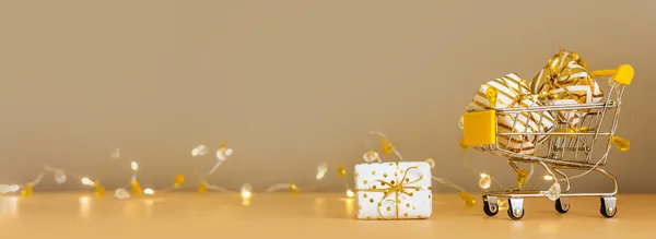 オンラインクリスマスショッピングと販売 ライト付きの黄金の背景にギフトボックス付きショッピングカート スーパートロリーフルプレゼント コピースペース付きバナー — ストック写真