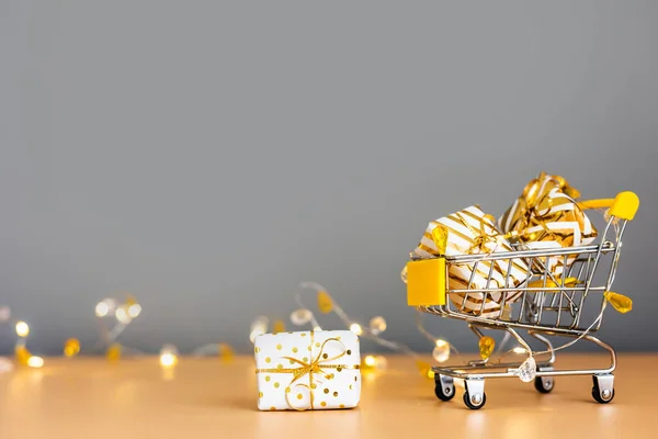 オンラインクリスマスショッピングと販売 ライト付きグレーの背景にギフトボックス付きショッピングカート スーパートロリーフルプレゼント スペースのコピー — ストック写真