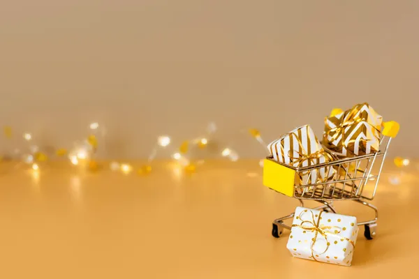オンラインクリスマスショッピングと販売 ライト付きの黄金の背景にギフトボックス付きショッピングカート スーパートロリーフルプレゼント スペースのコピー — ストック写真