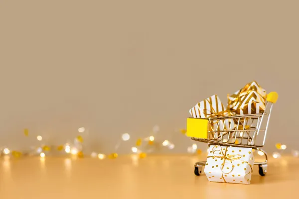 オンラインクリスマスショッピングと販売 ライト付きの黄金の背景にギフトボックス付きショッピングカート スーパートロリーフルプレゼント スペースのコピー — ストック写真