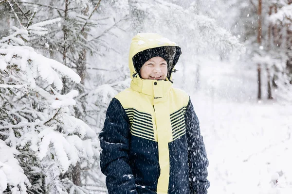 冬の森に降る雪を見て幸せな10代の少年 子供は屋外で楽しんでいます 雪の中で雪の中で遊ぶ楽しい青年 寒い日に冬の公園を歩く笑顔の子供 — ストック写真