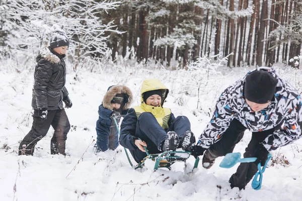 父と息子は一緒に冬の森をそり 楽しんでいます 雪の中で遊んでいる幸せな子供たちと若者 10代の男の子 かわいい幼児は霜の日に歩く 冬のアクティビティ — ストック写真