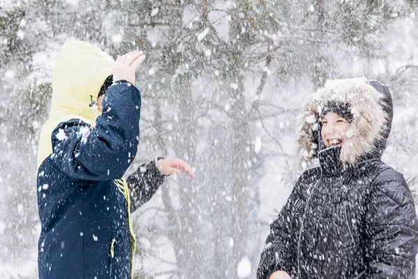 冬の森に雪が降っているのを見て幸せな10代の男の子 子供たちは屋外で楽しんでいます 雪の中で遊ぶ楽しい兄弟たち 寒い日に冬の公園を歩く笑顔の子供たち — ストック写真