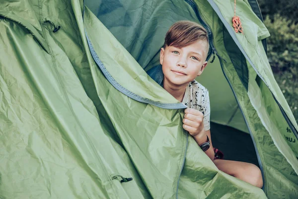 Teenager boy sitting in camping tent. Family weekend outdoor.