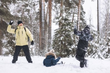 Baba ve oğulları kış ormanında kartopu savaşı yapıyorlar. Dışarıda karda oynayan mutlu çocuklar. Noel tatili, yeni yıl aile tatili. Sıcak giysili kardeşler soğuk günde yürürler.