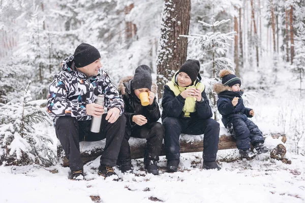 父と息子は魔法瓶からお茶を飲んで 冬の雪の森の中で一緒に座って話をします 冬の季節に屋外でピクニックをしている幸せな男 十代の男の子と幼児 地方旅行 スローライフ — ストック写真