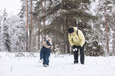 Baba ve oğulları kış ormanında kartopu savaşı yapıyorlar. Dışarıda karda oynayan mutlu çocuklar. Noel tatili, yeni yıl aile tatili. Sıcak giysili kardeşler soğuk günde yürürler.