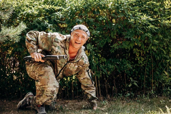 Man with a weapon in his hand playing laser tag shooting game in outdoor. War simulation game