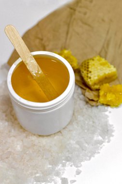 depilatory wax in a jar next to honeycomb and craft paper and wooden spatula