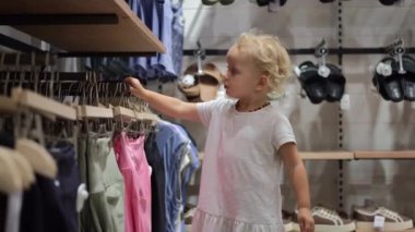 Sevimli, küçük bir kız giyim mağazasından şık bir kıyafet seçiyor.