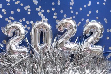 2022 gümüş sayılar konfetili mavi arka planda şişirilebilir rakamlar. Yeni yıl ve Noel konsepti