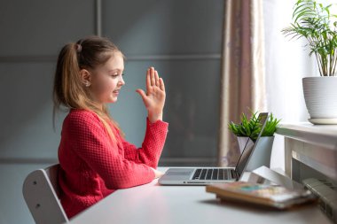 Mutlu küçük kız evde bilgisayar kullanarak online eğitim ve evde öğrenim görüyor. Çocuklar uzaktan öğreniyor. Sosyal mesafe. Evde kal..