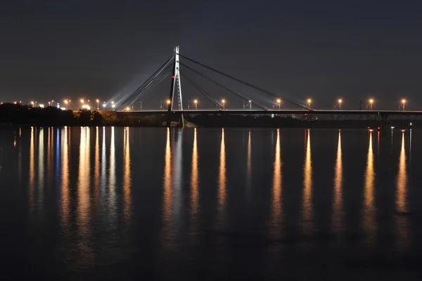 Híd fény tükrözi a vízben este — Stock Fotó