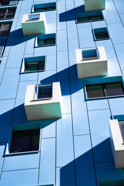 front view of a multi-storey blue modern building with small balconies