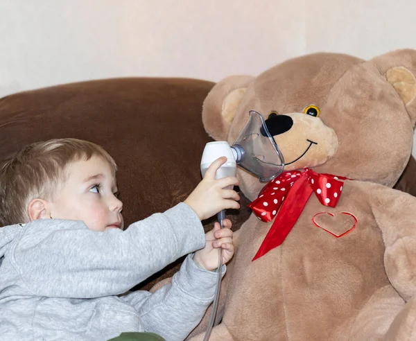 Pequeño niño jugando hace inhalación a un oso de peluche grande —  Fotos de Stock