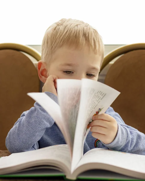 Πορτραίτο ενός σκεπτικού ξανθού παιδιού που ξεφυλλίζει ένα βιβλίο — Φωτογραφία Αρχείου