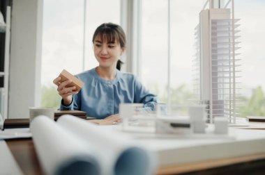 Seçici odak, Asyalı kadın mimar veya mühendis modern apartman daireleri tasarlamak için materyalleri değerlendiriyor. Asyalı kadın mimar ya da mühendis ofiste otur ve analiz et, tasarım projeleri