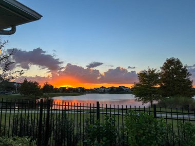 Güzel pembe, turuncu ve mavi gün batımı bir banliyö gölünde yansıyor..