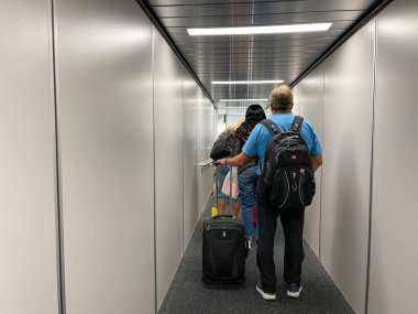 Orlando, FL USA - 23 Eylül 2021: Havaalanında uçağa binmek için jet yolunda yürüyen bir adam.
