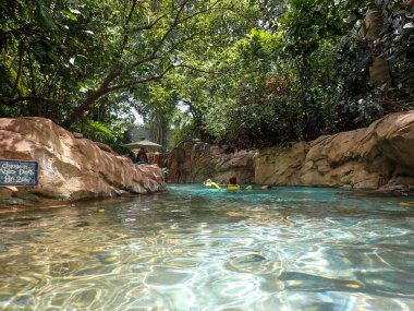 Orlando, FL USA - 21 Mayıs 2021: İnsanlar Orlando, Florida 'daki Discovery Cove Park' taki tembel nehir havuzu ve peyzajında yüzüyorlar.