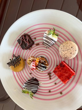 Kurabiye tepsisi, çikolata kaplı çilek, yer mantarı ve süslü bir tabakta kekler..