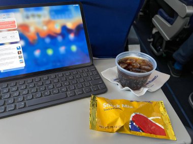 Orlando, FL USA - July 1, 2022: A drink and snack in front of a computer from a flight on Southwest Airlines Co. clipart