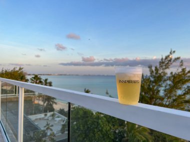 Cayman Islands - June 24, 2022:  An Inspirato glass with beer overlooking the Cayman Island coast at Seven Mile Beach.