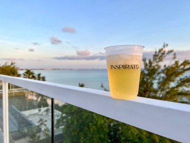 Cayman Islands - June 24, 2022:  An Inspirato glass with beer overlooking the Cayman Island coast at Seven Mile Beach.