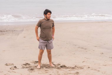 Genç adam plajda yoga yaparken çeşitli pozlar veriyordu. Harika bir günün ve güneşin tadını çıkarıyorum..