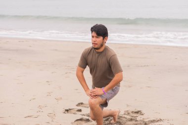 Genç adam plajda yoga yaparken çeşitli pozlar veriyordu. Harika bir günün ve güneşin tadını çıkarıyorum..