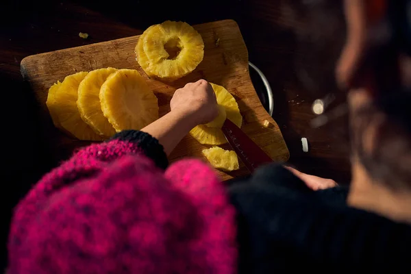 Kadın gün batımında ananas dilimleri kesiyor. Toparlanın.