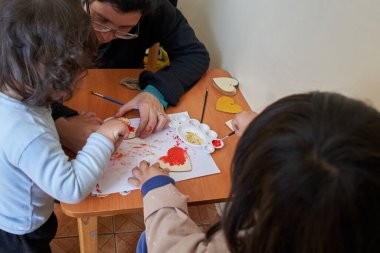 Anne ve iki çocuk kalp boyuyor. Sevgililer Günü