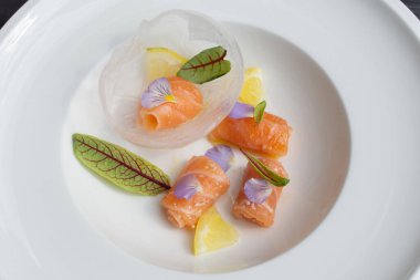 Salmon carpaccio with shio koji, yuzu juice, and olive oil in an ice sphere. Image can be utilized editorially or commercially.