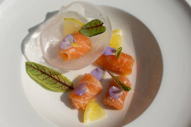 Salmon carpaccio with shio koji, yuzu juice, and olive oil in an ice sphere. Image can be utilized editorially or commercially.