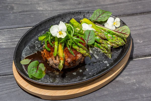 Hambagu (Hamburger Steak) with asparagus and green onion served on a cast iron pan