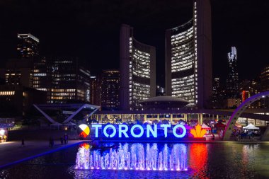 Toronto, ON, Kanada - 5 Ağustos 2022: Toronto tabelası gece aydınlandı, Nathan Phillips Meydanı 'nda Toronto Belediye Binası arka planda görüldü 