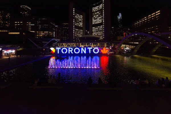 Toronto, ON, Kanada - 5 Ağustos 2022: Toronto tabelası gece aydınlandı, Nathan Phillips Meydanı 'nda Toronto Belediye Binası arka planda görüldü 