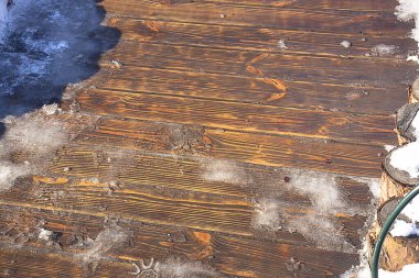 Snow melting on wooden planks. Thaw on wood flooring
