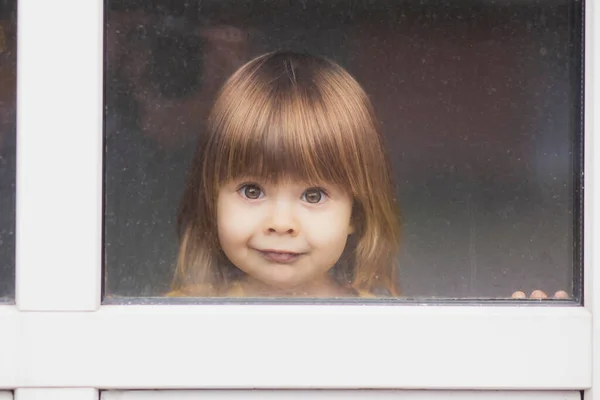 Piękne Jasnowłose Dziecko Wyglądające Przez Okno — Zdjęcie stockowe
