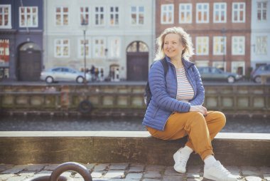 Blonde girl relaxing on the waterfront in Nyhavn in Copenhagen