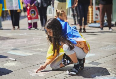 Aalborg, Danimarka, Haziran 2022: Danimarka 'da Ukrayna' yı destekleme eylemi. Ukrayna bayrağı taşıyan bir kız kaldırıma kalp çiziyor.. 