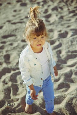 Charming child walking on the beach at sunset.