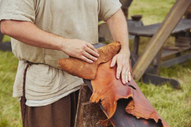 An artisan dressed in vintage clothing processes leather at a Viking festival in Denmark