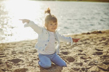 Charming child walking on the beach at sunset.