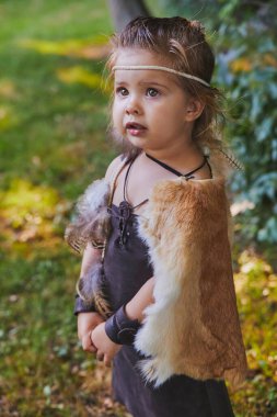 Cute baby dressed in the clothes of primitive people.
