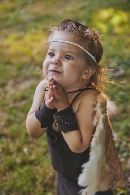 Cute baby dressed in the clothes of primitive people.