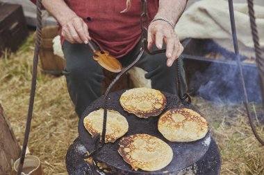 Kamp ateşinde tavada krep kızartan yaşlı adam..
